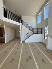 Unfurnished living room with a high ceiling, stairs, and recessed lighting