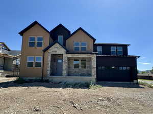 View of front of home featuring stone siding, a garage, driveway, and a porch