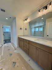 Bathroom featuring double vanity, a stall shower, and a spacious closet