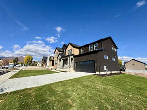 View of front of property featuring driveway, a front yard, a garage, and a residential view