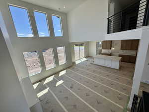 Unfurnished living room featuring a towering ceiling and recessed lighting
