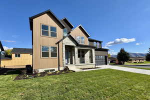 View of front of property with concrete driveway, a front yard, stone siding, a porch, and an attached garage