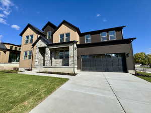 View of front of house with covered porch, an attached garage, a front lawn, driveway, and stone siding