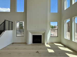 Unfurnished living room featuring a towering ceiling, plenty of natural light, and a fireplace with flush hearth