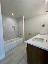 Bathroom with double vanity, shower / tub combination, and recessed lighting