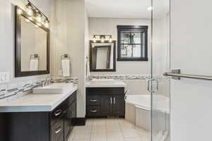 Full bathroom featuring two vanities, a bath, tile patterned floors, a shower stall, and backsplash