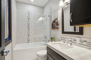 Full bathroom featuring vanity, shower / bathtub combination, decorative backsplash, and recessed lighting