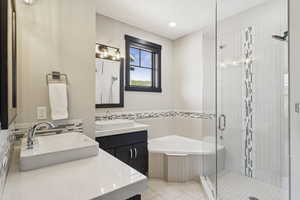Full bathroom featuring a stall shower, a bath, two vanities, tile patterned flooring, and tile walls