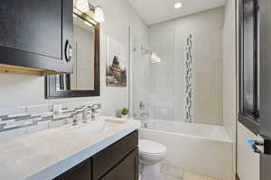 Full bathroom with vanity, washtub / shower combination, tasteful backsplash, and tile patterned flooring