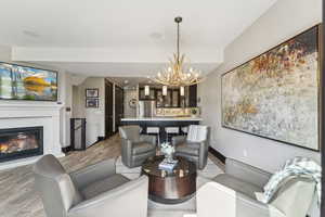 Living area with a chandelier, light wood finished floors, and a glass covered fireplace