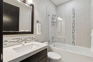 Full bath featuring vanity, bathing tub / shower combination, and tasteful backsplash