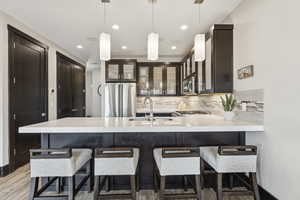 Kitchen with backsplash, light countertops, glass insert cabinets, appliances with stainless steel finishes, and a peninsula