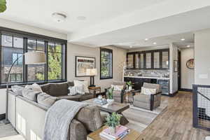 Living room featuring wine cooler, bar, light wood finished floors, and recessed lighting