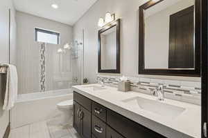 Bathroom with double vanity,  shower combination, recessed lighting, and decorative backsplash