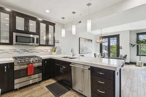 Kitchen with appliances with stainless steel finishes, light countertops, a peninsula, and recessed lighting