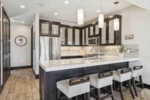 Kitchen featuring appliances with stainless steel finishes, light countertops, tasteful backsplash, a peninsula, and a breakfast bar area