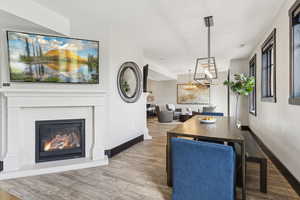 Dining room with a glass covered fireplace, wood finished floors, and a chandelier
