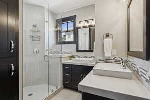Full bathroom featuring a shower stall, vanity, tile patterned flooring, and decorative backsplash