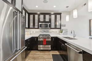 Kitchen with high quality appliances, light wood-style flooring, decorative backsplash, light countertops, and recessed lighting