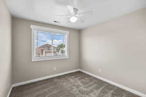 Spare room featuring ceiling fan, dark carpet, and a textured ceiling