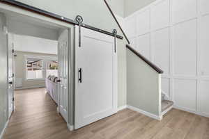 Corridor featuring light wood-type flooring, a barn door, and stairway