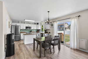 Dining space with light wood-style flooring, a chandelier, and heating unit