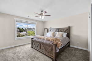 Carpeted bedroom featuring baseboards and a ceiling fan