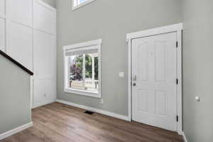 Foyer with healthy amount of natural light, wood finished floors, and a high ceiling