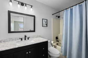 Bathroom with vanity, shower / tub combo, and a textured ceiling