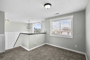 Empty room featuring a textured ceiling and dark colored carpet