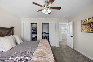 Carpeted bedroom with multiple closets, ceiling fan, and a textured ceiling
