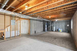 Unfinished basement featuring water heater, electric panel, and heating unit