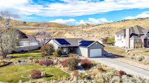 Ranch-style house with a garage, driveway, roof mounted solar panels, and a mountain view