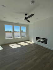 Unfurnished great room featuring fireplace, light wood-style floors, and ceiling fan