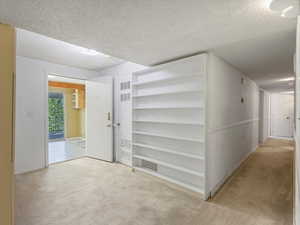 Hall with light carpet, a textured ceiling, and a heating unit