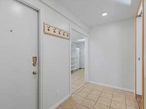 Hallway featuring light tile patterned floors and baseboards