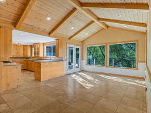 Kitchen with french doors, wood ceiling, a wainscoted wall, glass insert cabinets, and a peninsula