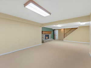 Finished basement with a fireplace, carpet flooring, and stairs
