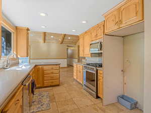 Kitchen with light brown cabinetry, recessed lighting, appliances with stainless steel finishes, light countertops, and a peninsula