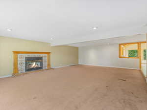 Unfurnished living room featuring carpet, recessed lighting, and a tile fireplace