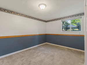 Carpeted spare room featuring baseboards