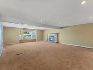 Unfurnished living room featuring carpet flooring, recessed lighting, and a fireplace