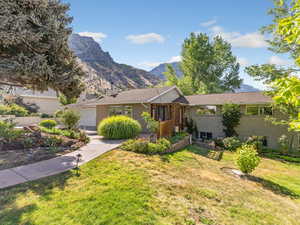 Ranch-style home with a front lawn, a mountain view, and brick siding