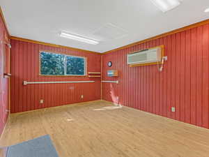 Spare room featuring wood finished floors, attic access, wood walls, and a wall mounted AC