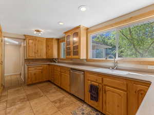 Kitchen featuring stainless steel dishwasher, glass insert cabinets, light countertops, and recessed lighting