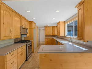 Kitchen with stainless steel appliances, recessed lighting, a peninsula, and light brown cabinets