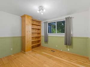 Empty room featuring wainscoting and wood-type flooring