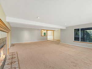 Unfurnished living room with a fireplace, light carpet, and recessed lighting
