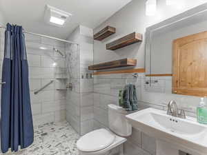 Full bathroom with a stall shower and tile walls