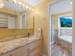 Bathroom with wood finished floors, vanity, a bath, and a stall shower